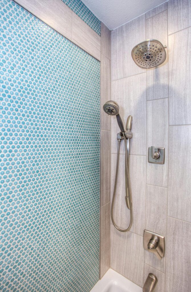Elegant shower design featuring blue mosaic tiles and stainless steel fixtures.